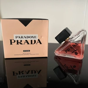 Prada Paradoxe Intense EdP 50ml - Prada Paradoxe Intense Eau de Parfum i en unik trekantig glasflaska med svart lock och rosa doftvätska. Lyxig och modern design, 50 ml, kommer i en stilren ljusrosa kartong. Perfekt för dig som vill ha en statement-parfym från ett ikoniskt modehus.