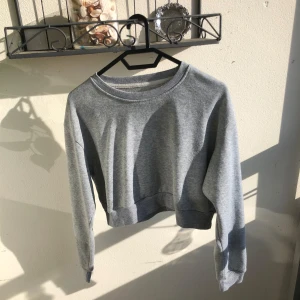 Grå croppad sweatshirt - Enkel och basic grå croppad sweatshirt med rund halsringning och långa ärmar. Tröjan har ribbade muddar vid ärmslut och nederkant. Den är S men är typ S/M oxå. den är gjord i lite tunnare bomull. så pssar bra på sommarn oxå