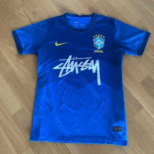 Blå Brasil Nike x Stüssy fotbollströja - Snygg blå Brasil fotbollströja från Nike i samarbete med Stüssy. Tröjan har korta ärmar, gul Nike-logga sick 10-10 stolek m passar bättre i S🙂