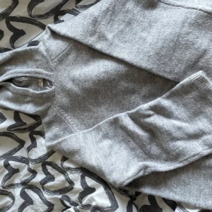 Grå stickad polotröja Gina Tricot - Mysig grå stickad polotröja från Gina Tricot i storlek S. Tröjan har en hög polokrage och långa ärmar, perfekt för kyliga dagar. Den är enkel att matcha och har en klassisk, avslappnad passform.