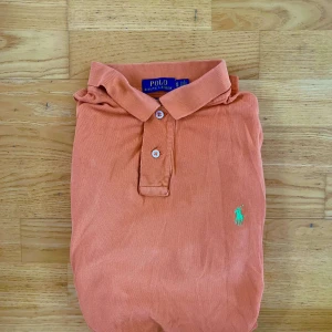 Ralph Lauren piké - Säljer en orange pikétröja från Polo Ralph Lauren i klassisk modell. Står XL men skulle hellre säga att den sitter som L.