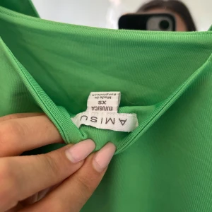 Grön linnetopp från Amisu - Snygg grön linnetopp från Amisu med breda axelband och fyrkantig ringning. Toppen är enkel och stilren, perfekt att matcha med jeans eller kjol. Tillverkad i mjuk bomull som känns skön mot huden.