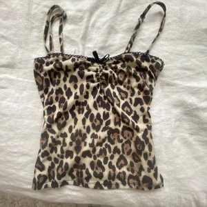 Leopardmönstrad linnetopp med rosett - Säljer en leopardmönstrad linnetopp med smala axelband och söt svart rosett framtill. Storlek xs