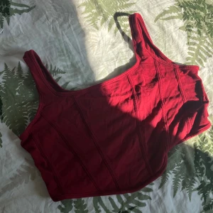Mörkröd ”korset” top  - En röd topp med korsettsömmar (som är mjuka utan plast eller metall). Den är bekväm och lätt att styla med alla möjliga kläder🌸har använts få gånger och är nästan som ny ☺️