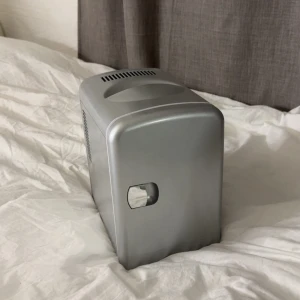 Sminkkylskåp i silver - Sladd ingår Snyggt sminkkylskåp i metallic silver med vit insida. Perfekt för att hålla dina hudvårdsprodukter och smink svala. Har både AC- och DC-anslutning samt möjlighet att välja mellan kallt och varmt läge. Kompakt och stilren design som passar på sminkbordet.