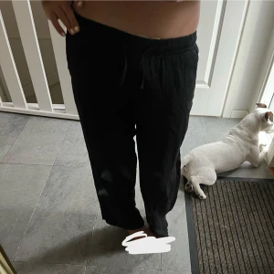 Svarta linnebyxor - Säljer ett par svarta linnebyxor med avslappnad passform och resår i midjan samt snörning. Byxorna har raka ben och är perfekta för en chill och stilren look. Superbekväma och lätta att matcha med det mesta. 