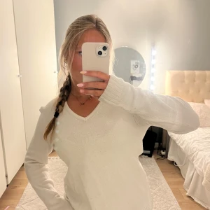 Vit stickad v-ringad tröja från Vila - Vit stickad tröja från Vila med v-ringning och långa ärmar. Enkel och clean design som passar perfekt till jeans eller kjol. Mjuk och skön känsla, ribbade muddar vid ärmslut och nederkant. Perfekt för lager-på-lager under kyliga dagar.