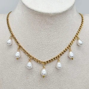 Handgjort halsband  - Stilrent halsband med chunky guldfärgad kedja och sju droppformade vita pärlor som hänger längs kedjan. Rostfrit stål, pärlor. Längd-40cm,kedjetjocklek-4cm