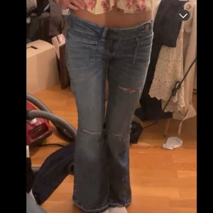 Blå bootcut jeans med slitningar - Snygga blå jeans med bootcut-modell och slitningar vid knäna. Jeansen har låg midja och klassiska fickor fram och bak. Från Gina 14+ i regular