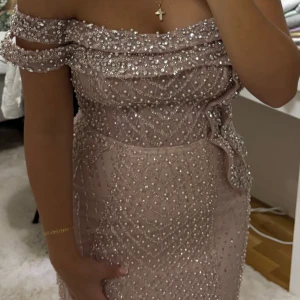 Festklänning - Ljusrosa/champange glittrig långklänning - Superfin ljusrosa/champagne långklänning med offshoulder och massor av pärlor och paljetter. Klänningen har figurnära passform, dragkedja bak och vackra detaljer som ger en lyxig känsla. Perfekt för bal eller festliga tillfällen! Köpt för 7900 från edessas mode, i storlek 34-36, och har endast använts i några timmar. 🤍 