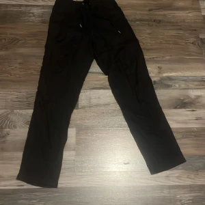 Svarta byxor med snörning från H&M - Svarta linnebyxor från H&M i storlek XS. De har resår och snörning i midjan för skön passform och raka ben. Materialet känns lätt och svalt, perfekt för chill dagar. Snygga att matcha med en hoodie eller t-shirt.