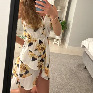 Vit blommig kortklänning med volang - Säljer en superfin vit kortklänning med gula och svarta blommor. 