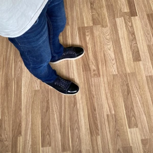 Svarta lanvin cap toe  - Snygga svarta lanvin sneakers med cool lackad tå och ovandel i mocka. Skorna är i storleken uk 6 som motsvarar 40-41. Skorna har snörning och en beige platt sula som ger en klassisk vibe. Perfekta för dig som gillar stilrena detaljer och vill sticka ut med en unik look. De är i ganska bra skick,skriv till mig vid minsta fundering.Ingen og medföljer tyvärr. Några säger att de ser marinblå ut men jag tycker att de ser i mestadels svarta ut.Skriv till mig när ni ska köpa.🤔 😃💸 Mvh Emil