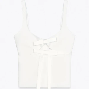 Vit linnetopp med rosetter - Supersöt vit linnetopp med två dekorativa rosetter framtill. Toppen har breda axelband och en stilren, rak passform som ger en fräsch och modern look. Perfekt att matcha med jeans eller kjol för en trendig vibe. Nypris 379kr, endast använd en gång