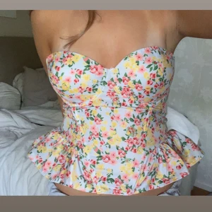 Blommig korsettopp med peplum - En jätte fin topp jag säljer då jag inte använder den! Den är i otroligt bra skick och de går att vika ner banden för bandeu modell🩷 de går att justera både banden och storleken med hjälp av snörningen💝