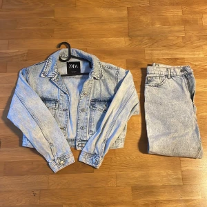 Ljusblå jeansjacka från ZARA - Snygg ljusblå jeansjacka från ZARA med klassisk krage och silverfärgade knappar. Jackan har två bröstfickor med lock och är croppad i modellen. Perfekt för dig som gillar retrovibbar och vill ha en cool denimlook. Och den är använd två gånger 