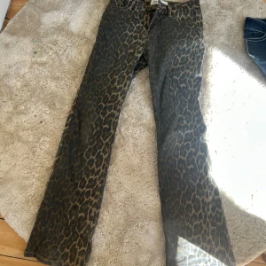 Leopardmönstrade jeans från Sofie Schnoor🌟 - Snygga jeansbyxor från Sofie Schnoor med leopardmönster i mörkgrå och beige toner. Modellen har rak passform och klassisk femficksdesign med dragkedja och knapp framtill. Perfekt för dig som vill sticka ut med coola detaljer och djurprint.