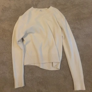 Vit stickad tröja från Uniqlo - Snygg vit stickad tröja från Uniqlo med rund hals och långa ärmar. Tröjan har ribbade muddar vid ärmslut. Perfekt för lager-på-lager under hösten och vintern. Köpt för 450 kr