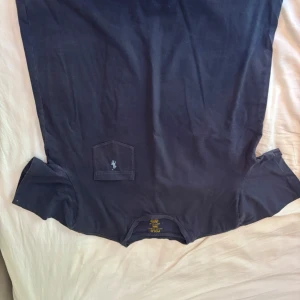 Svart t-shirt Polo Ralph Lauren M - Svart t-shirt från Polo Ralph Lauren i stretchig bomull. Klassisk rund hals och korta ärmar. Bröstficka med liten broderad logga i ljusblått. Enkel och stilren design som funkar till jeans eller shorts. Snygg polo tröja men kragen lite ful och lite solblek men annars fin