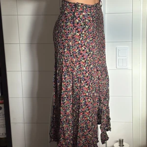 Blommig långkjol från Ebba Jensen - Supersöt långkjol från Ebba Jensen med blommigt mönster. Kjolen har slitsar och är gjord i mjuk och flowy viskos. Perfekt för dig som gillar romantisk och färgglad stil. Knappt använd eller slitage. Finns belt-loops för ett fint bälte. ❤️