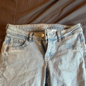 Bootcut ljusblå jeans från &Denim - Snygga ljusblå bootcut jeans från hm i storlek 34. Modellen har låg midja, klassisk femficksdesign och dragkedja med knapp framtill. Jeansen är tillverkade i mjukt denimtyg och har en  bootcut-passform