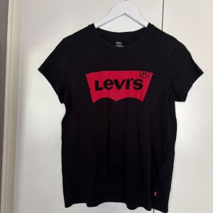 Svart Levi's t-shirt med röd logga - Svart T-shirt från Levis med ett rött tryck. Varsamt använd och mycket bra skick, storlek S. 