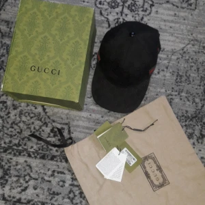 Gucci keps - Säljer en svart keps från Gucci med klassiskt GG-monogram över hela kepsen. Snygg detalj med röd och grön rand på sidan och justerbar rem i skinn baktill. Materialet är bomull och skinn, och kepsen kommer med originalkartong och dustbag, den är 100%ekta och har med sig prislapp oxå!!! Helt sjuk Gucci keps du kan inte ångra dig😁🤝