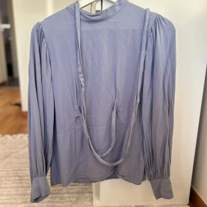 En skön blus med extra detaljer - Har två band som kan knytas fram eller bak. Ryggen var öppen men jag har sytt igen den pả ett fint sätt for en ny och unik design.
