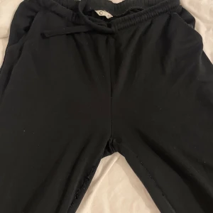 Svarta mjukisbyxor med snörning - Svarta mjukisbyxor från Cubus i storlek M. De har elastisk midja med snörning för skön passform och är gjorda i mjukt bomullsmaterial. Perfekta för chill dagar eller när du vill vara bekväm. Klassisk rak modell utan synliga detaljer eller mönster.