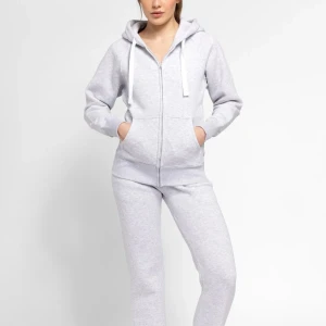 Ljusgrå hoodie med dragkedja - Ljusgrå hoodie med huva och vita snören, hel dragkedja framtill och två fickor. Mjuk och skön i bomullsmix, perfekt för chill dagar. Långärmad med ribbade muddar och avslappnad passform. Enkel och stilren design som funkar till allt.