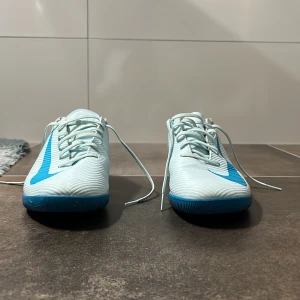 Nike Mercurial ljusblå innomhus fotbollsskor - Säljer ett par ljusblåa Nike Mercurial innomhus fotbollsskor. Skorna är använda ett antal gånger men är i väldigt bra skick ändå. Skorna är i storlek 42 och extremt sköna, jag skulle säga att de passar någon som har lite smalare fötter. Om du har någon fundering är det bara att fråga😄😄😄