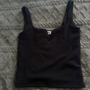 Svart linnetopp med V-ringning Kappahl - Svart linnetopp från Kappahl i storlek XS. Toppen har breda axelband och en snygg V-ringning framtill som ger en cool touch. Materialet känns mjukt och stretchigt, perfekt för att styla med jeans eller kjol. Enkel och stilren design som funkar till många looks.