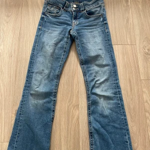 Blå low waisted bootcut jeans från Gina tricot young  - Snygga blå jeans med bootcut passform. Klassisk femficksmodell med knapp och dragkedja. Jeansen har en cool tvätt och är perfekta för en avslappnad stil. Två knappar framtill och normala fickor baktill. Super fina ❣️