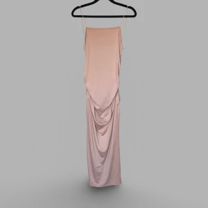 Champagnefärgad långklänning med urringad rygg - Säljer en elegant långklänning i champagnefärgad ton med smala axelband och snygg urringning och detalj baktill. Klänningen har en draperad effekt både fram och bak. 