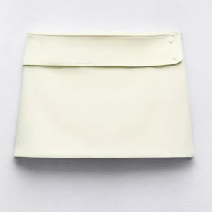 Off white kortkjol från Zara - Superfin kortkjol från Zara med bred linning och två dekorativa knappar i midjan. Lite nopprig se bild. Färgen är off white, den har en svag ton av gul i färgen. 