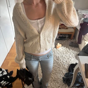 Beige stickad kofta med knappar - Supermysig beige stickad kofta med v-ringning och snygga detaljer i stickningen. . Perfekt att slänga över en topp för en chill look.
