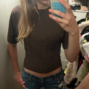 Figursydd topp - Säljer en supersöt figursydd T-shirt  med korta ärmar och rund hals. Perfekt till jeans eller shorts för en chill och avslappnad look. Materialet känns mjukt och lätt mot huden.