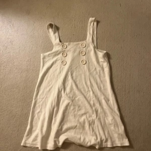 Vit kort klänning/tröja med knappar🤍 - Väldigt söt, kan användas som kort ”miniklänning” eller alternativt tröja 😊lite nopprig men annars fint skick. 