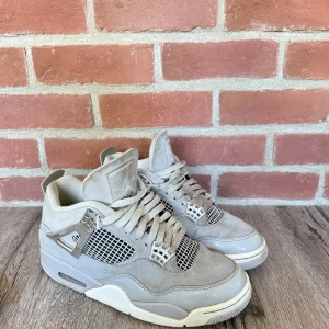 Nike Air Jordan 4 grå mocka sneakers - Säljer ett par Nike Air Jordan 4 sneakers i grå mocka med coola metalliska detaljer och meshpaneler. Skorna har snörning, platt sula och den klassiska Jumpman-loggan på hälen. Perfekt för dig som gillar streetstyle och vill sticka ut med ett par ikoniska sneakers
