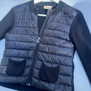 Svart Moncler cardigan jacka  - Snygg svart pufferjacka från Moncler med quiltad framsida, ribbad krage och ärmar i stickad material. Jacka passar xs/s/m. Skriv om du undrar nått eller vill ha fler bilder 