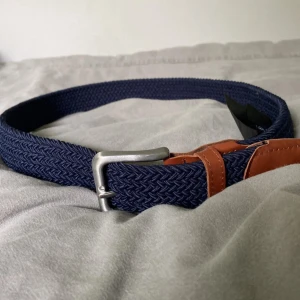 Blått flätat bälte från Jack & Jones - Snyggt blått flätat bälte från Jack & Jones med detaljer i brunt skinn och silverspänne. Perfekt accessoar för att lyfta din outfit. Bältet har längd 80 och klassisk design.
