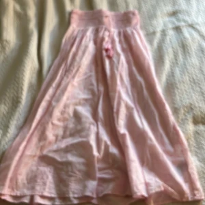 Ljusrosa långkjol från Gina Tricot - Supersöt ljusrosa långkjol från Gina Tricot med smock i midjan och knytband med tofsar. Hör av er om ni har några funderingar💕kan diskutera priset💕.