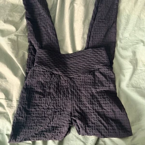 Svarta scrunch leggings - Säljer ett par svarta leggings med scrunch-effekt bak och hög midja. De är tillverkade i ett stretchigt, texturerat syntetmaterial som ger en cool look och sitter riktigt skönt. Perfekta för träning eller chill dagar.