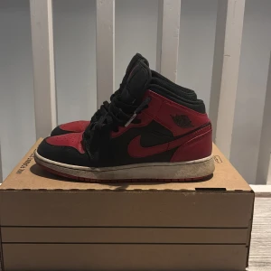 Nike Air Jordan 1 High röd/svart EUR 38 - Säljer ett par klassiska Nike Air Jordan 1 High i svart och rött skinn med svarta snören och röd yttersula. Ikonisk siluett med högt skaft, perforerad tå och broderad Jumpman-logga på plösen. Perfekta för dig som vill sticka ut med en tidlös sneaker.  Pris går att diskutera 
