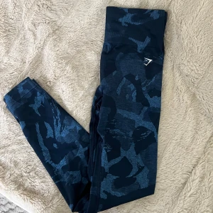 Blå camo leggings från Gymshark - Snygga blå leggings från Gymshark med camo-mönster och hög midja, stretchigt material som sitter skönt. Materialmix av polyamid, polyester och elastan.
