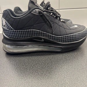 Nike Air Max 720 svarta sneakers - Svarta Nike Air Max 720 sneakers med coolt rutmönster i vitt runt sulan och hälen. Skorna har en stor genomskinlig luftbubbla i sulan, snörning och broderade vita swoosh-loggor på tån. Ovandelen är i syntetmaterial med quiltade sömmar för extra stil.