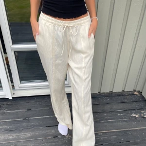 Linnebyxor Zara - Snygga ljusa linnebyxor i beige/vit med avslappnad passform. Byxorna har resår i midjan och snörning framtill. Perfekta för en stilren look. Byxorna är endast testade och har inga tecken på användning.