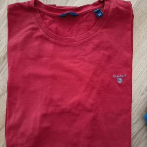 Röd t-shirt från GANT i bomull - Röd t-shirt från GANT med klassisk rund hals och liten broderad logga på bröstet. Tillverkad i mjuk bomull som känns skön mot huden. Perfekt basic-plagg med clean look och snygg passform.
