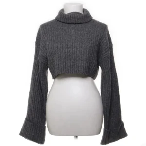 Grå stickad polotröja - Supermysig mörkgrå croppad polotröja med långa ärmar och ribbad stickning. Tjockt och mjukt material som håller dig varm under kyliga dagar. Storlek XS.
