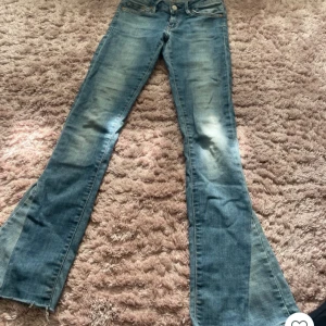 Bootcut jeans från Crocker, ljusblå - Bootcut jeans från Crocker i ljusblå denim med slitningar och snyggt utsvängda ben. Låg midja och klassisk femficksmodell. Jeansen har råa kanter nertill för en extra cool vibe. Perfekta för dig som gillar retrostil och vill sticka ut.
